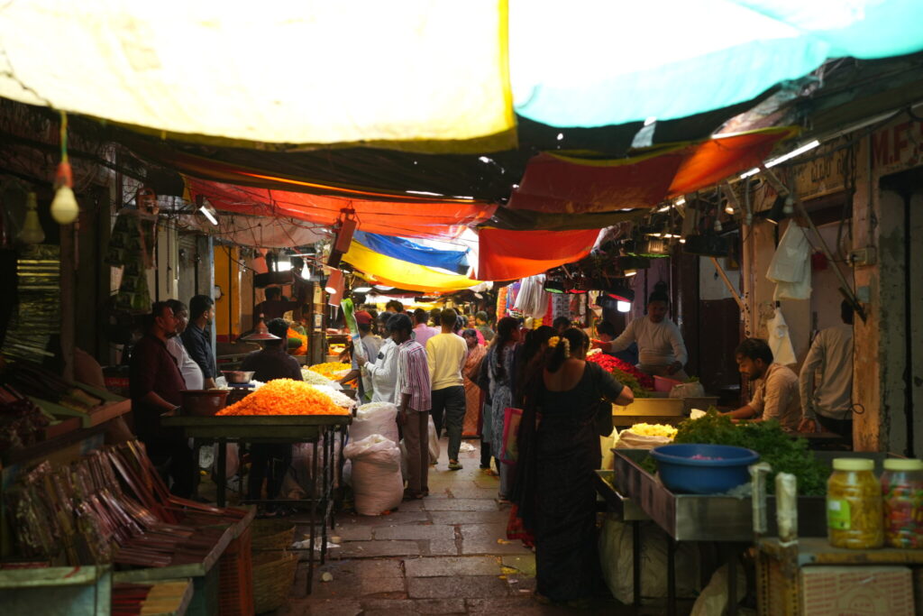 Pasillo del mercado Devaraja en Mysore lleno de flores, especias y puestos tradicionales bajo toldos de colores