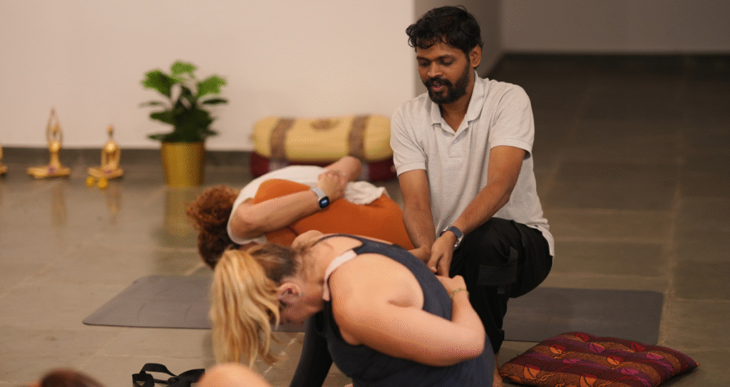 Ajuste manual en la práctica de Ashtanga Yoga durante un retiro de yoga en Mysore