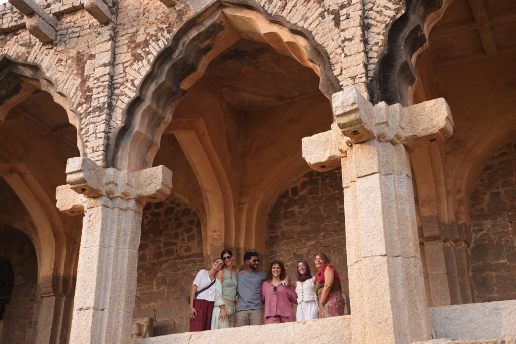 Grupo del retiro de yoga en Hampi bajo arcos de piedra históricos
