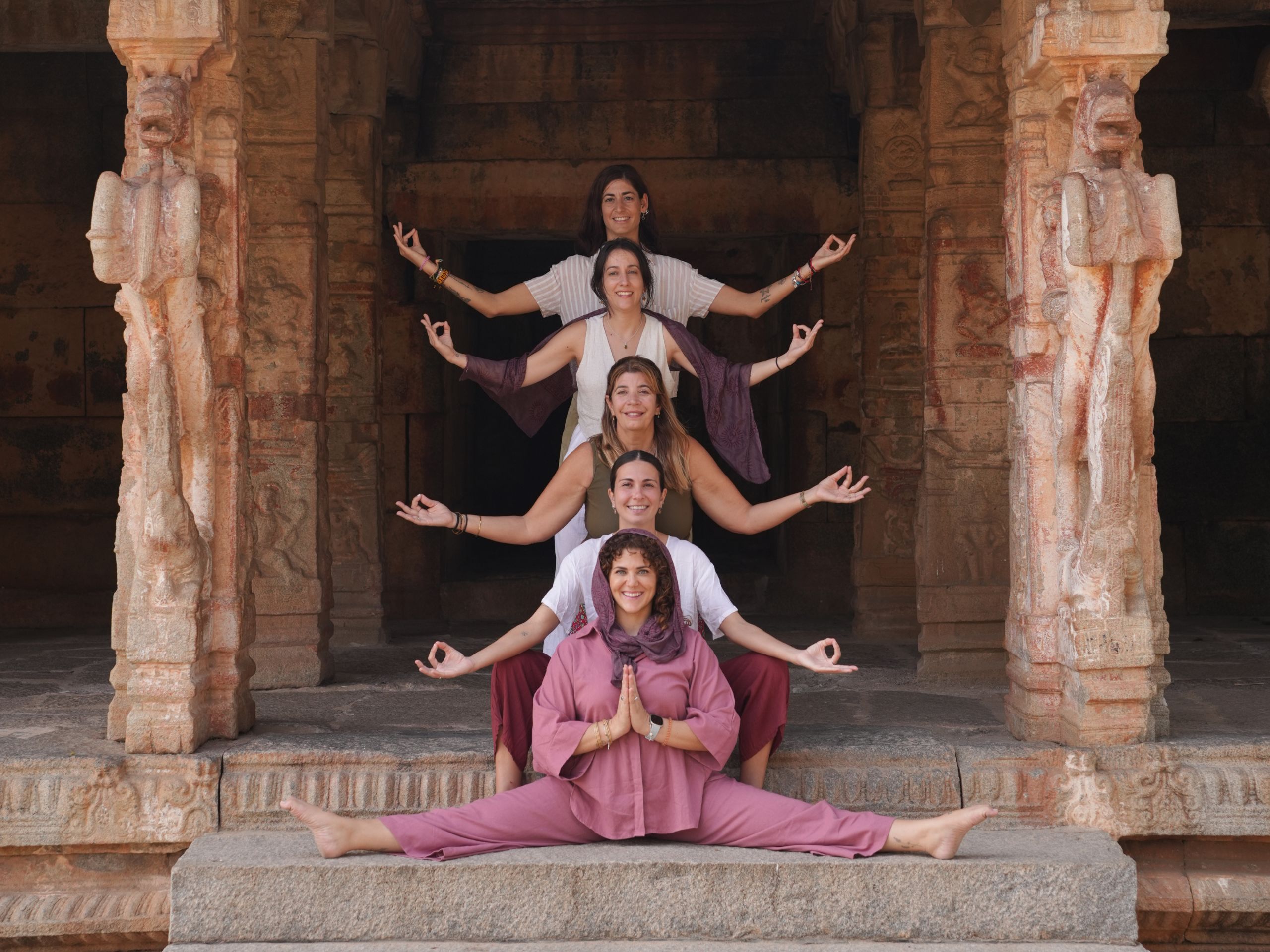 Grupo de mujeres del retiro de yoga posando juntas en un templo antiguo de Hampi