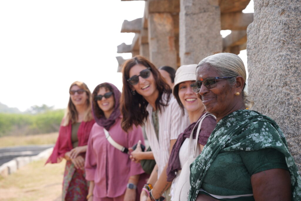 Interacción entre participantes del retiro de yoga y una mujer local en Hampi
