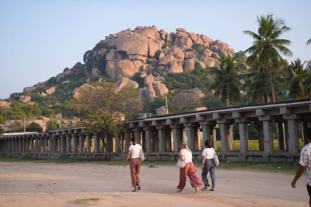 Personas caminando entre ruinas y paisajes naturales en Hampi