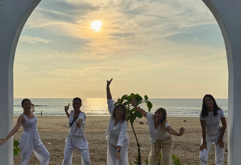 Participantes del retiro de yoga en Gokarna posando juntas en la playa al atardecer