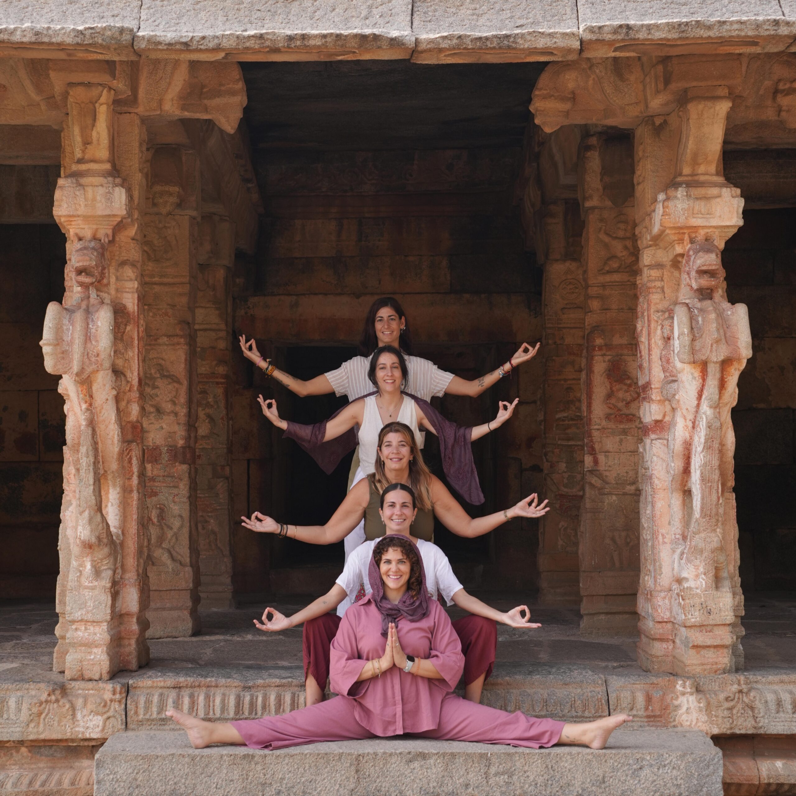 Grupo de mujeres del retiro de yoga posando juntas en un templo antiguo de Hampi